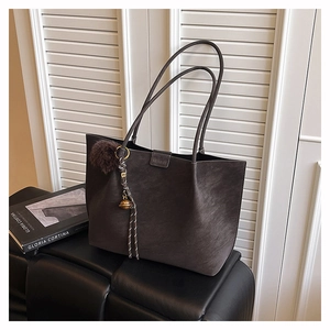 Close-up of a large coffee brown suede tote bag with stylish shoulder straps and charm