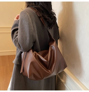 Close-up of stylish brown leather tote bag showing slouchy texture and wide shoulder strap