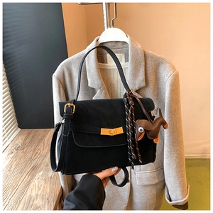 Detail of black vintage square bag with gold twist lock and silk scarf on grey suit