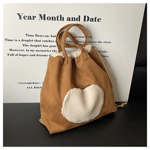 Detail of vintage brown suede tote bag featuring cream white fleece heart embroidery