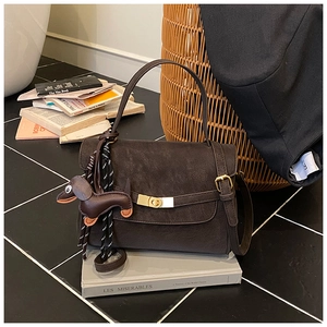 Detail of dark brown vintage shoulder bag with a cute dachshund leather charm and gold clasp