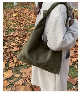 Detail of a deep olive green suede tote bag with a unique knot strap design on the shoulder