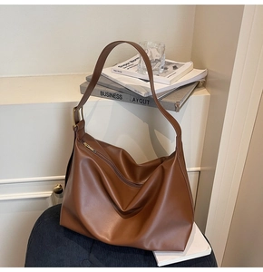 Detail view of large brown tote bag showing matte leather texture and gold metal buckle