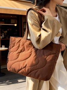 Deep brown quilted puffer tote bag with wave stitching and wide shoulder straps