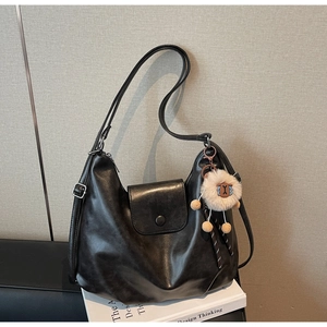 Detail of black large hobo bag with vintage texture and cute sheep plush pendant charm