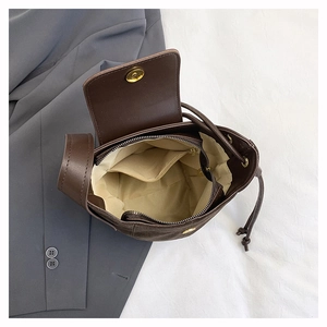 Detail view of the brown suede bucket bag showing the interior lining and zipper pocket