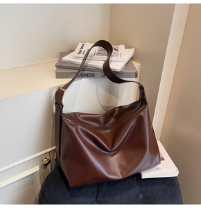 Detail view of large brown faux leather tote bag with wide adjustable shoulder strap