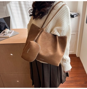 Detail of brown frosted leather tote bag set with branded text shown on female model
