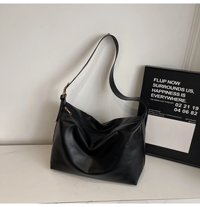 Close-up of black leather hobo bag with vintage gold metal buckle on marble surface