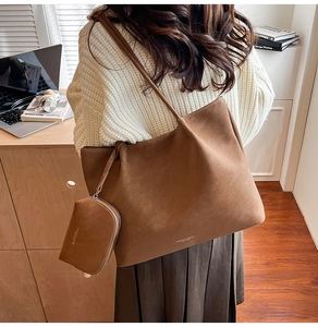 Brown suede tote bag with matching inner pouch shown in a warm minimalist office setting