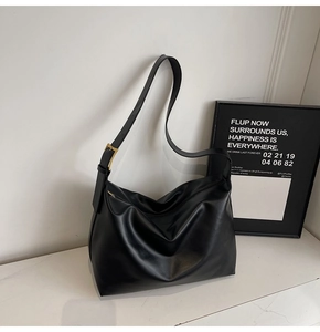 Detail of the golden square metal buckle on a black minimalist large capacity hobo bag