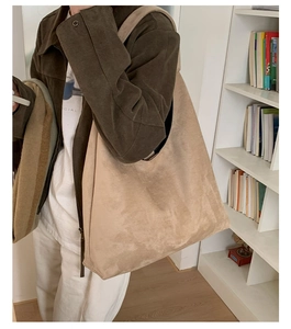 Detail view of khaki suede tote bag with wide shoulder strap worn in an office setting