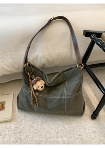 Detail of green tote bag with white cross-stitch pattern and brown leather strap