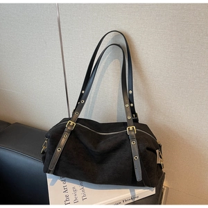 Detail of minimalist matte black shoulder bag with gold metal eyelets and leather straps