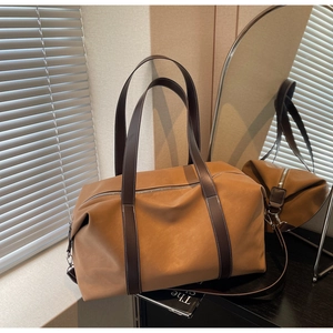 Detailed close-up of premium brown leather travel bag with contrast stitching and silver zipper
