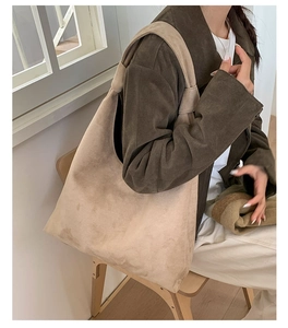 Detailed view of spacious beige suede tote bag styled with a neutral outfit