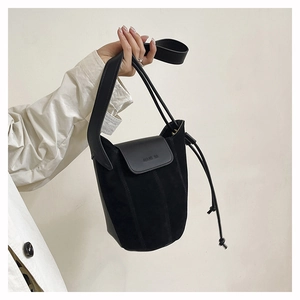Detail of black suede bucket bag featuring ALANA HA embossed logo and thick strap