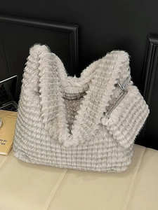 Minimalist grey faux fur tote bag with matching small pouch on a soft beige ottoman