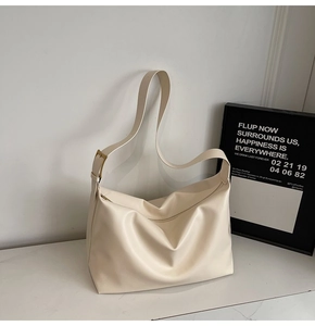 Detail of cream white leather tote bag with wide shoulder strap and gold buckle hardware