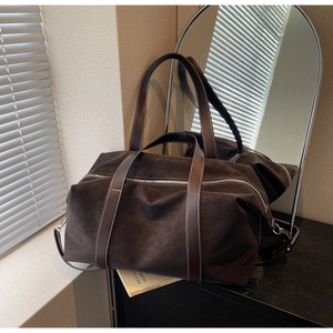 Macro shot of dark coffee suede travel bag with silver zipper and leather shoulder strap