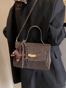 Retro brown crossbody bag with dachshund charm and tassel on a female model