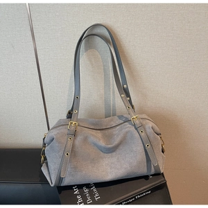 Close-up of gray suede tote bag featuring slim straps and gold metal eyelet details