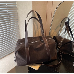 Detailed view of deep brown travel bag with silver metal zippers and smooth matte texture