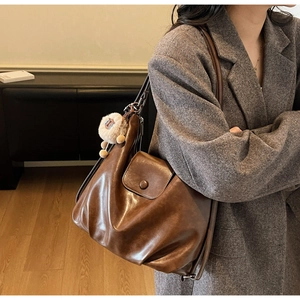 Detailed shot of brown vintage PU leather tote bag with a soft plush sheep pendant accessory