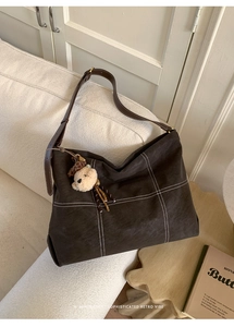 Detail of dark brown matte tote bag with contrast stitching and teddy bear charm