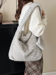 Grey plush tote bag with checkered texture shown on model in cozy indoor setting