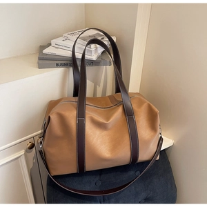 Detail of light brown leather travel tote with dark brown straps and zipper closure