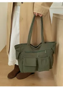 Detail of forest green corduroy tote bag showing functional multi-pocket design on the front