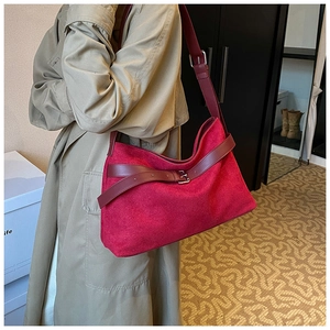 Close-up of a burgundy suede tote bag with leather strap and metal buckle details