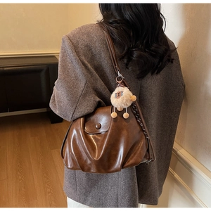 Detail of vintage brown soft leather underarm bag with decorative plush lamb charm