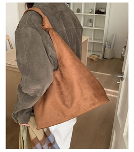 Close-up of a large brown suede tote bag with a knotted strap and a minimalist hobo design
