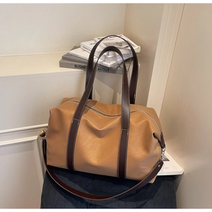 Detail of camel brown PU leather travel bag with contrast stitching and metal zipper