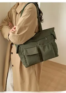 Detail of dark green corduroy shoulder bag featuring multiple pockets and soft texture