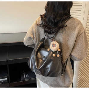 Detail of soft black leather shoulder bag with magnetic snap and plush lamb charm