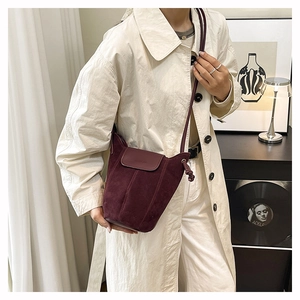 Detail of burgundy frosted suede bucket bag with leather flap and drawstring knots