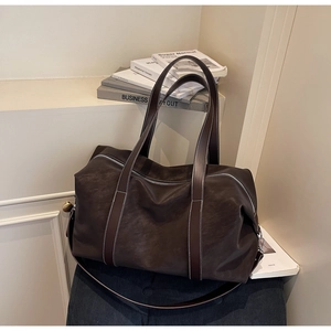 Detail of large dark brown travel tote bag with contrast stitching and leather texture