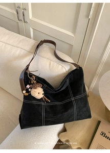 Detail of retro black matte tote bag with white stitching and a cute dog plush pendant