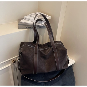 Close-up of dark brown leather tote bag with white stitching and silver zipper detail