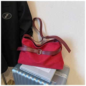 Détail du sac cabas mat bordeaux avec boucle argentée posé sur une valise en métal