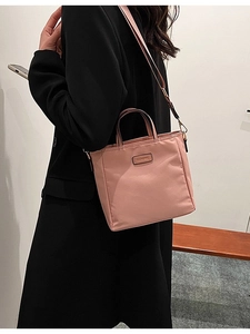 Pink nylon crossbody bucket bag with adjustable strap and top handles for casual wear