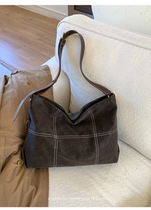 Detailed view of dark brown frosted tote bag with white cross-stitch and gold buckle