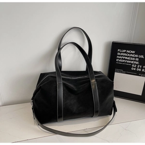 Detail of a large black tote bag with white contrast stitching and a removable strap