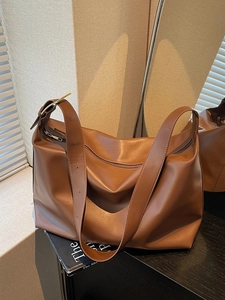 Brown large capacity leather tote bag with wide shoulder strap and gold hardware