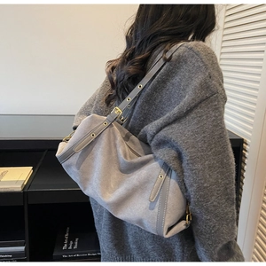 Detail of adjustable strap with gold eyelets on a matte grey suede shoulder bag