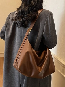 Brown leather large capacity hobo bag worn by model over a grey wool coat back view