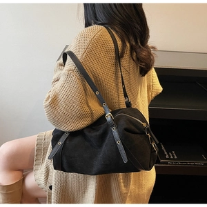 Close-up of black suede hobo bag with adjustable eyelet leather strap and metal buckle detail